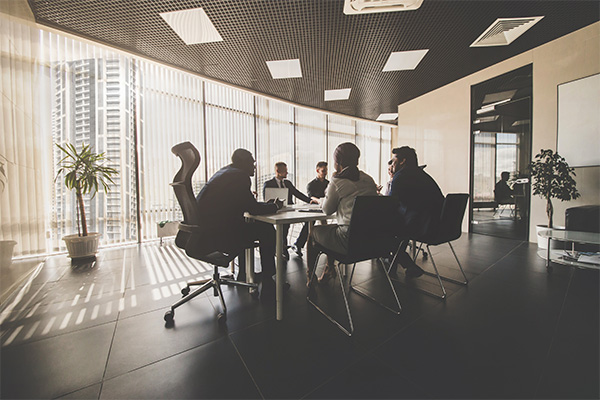 an image of several people in a meeting room at a table